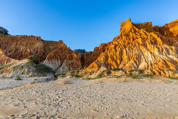 Bir çakıl taşı ve kumsalda inanılmaz kaya oluşumu. Kızıl topraklı kızıl kayalıklar ve kumlu sahilde inanılmaz oluşumlar. Praia da Falsia, sıcak güneş ışığıyla yıkanmış, Algarve, Portekiz