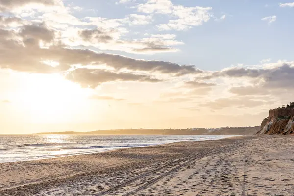 Okyanus kıyısında inanılmaz bir kaya oluşumu. Kızıl toprağı ve geniş kumsalda çarpıcı oluşumları olan kızıl kayalıklar. Praia da Falsia, güneş batarken sıcak bir ışıkta yıkandı, Algarve, Portekiz
