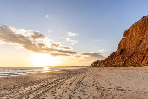 Okyanus kıyısında inanılmaz bir kaya oluşumu. Kızıl toprağı ve geniş kumsalda çarpıcı oluşumları olan kızıl kayalıklar. Praia da Falsia, güneş batarken sıcak bir ışıkta yıkandı, Algarve, Portekiz