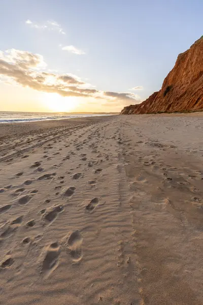 Okyanus kıyısında inanılmaz bir kaya oluşumu. Kızıl toprağı ve geniş kumsalda çarpıcı oluşumları olan kızıl kayalıklar. Praia da Falsia, güneş batarken sıcak bir ışıkta yıkandı, Algarve, Portekiz