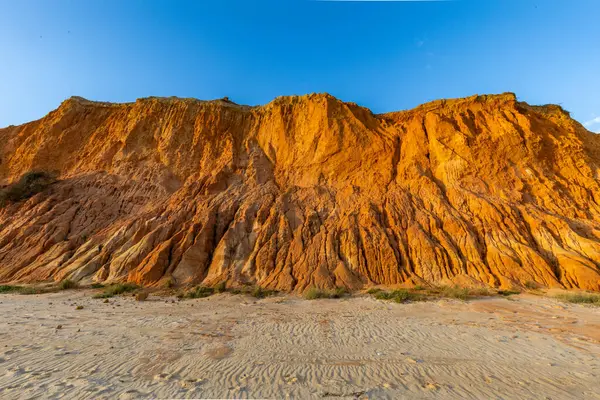 Bir çakıl taşı ve kumsalda inanılmaz kaya oluşumu. Kızıl topraklı kızıl kayalıklar ve kumlu sahilde inanılmaz oluşumlar. Praia da Falsia, sıcak güneş ışığıyla yıkanmış, Algarve, Portekiz