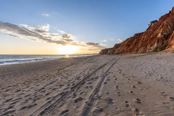 Okyanus kıyısında inanılmaz bir kaya oluşumu. Kızıl toprağı ve geniş kumsalda çarpıcı oluşumları olan kızıl kayalıklar. Praia da Falsia, güneş batarken sıcak bir ışıkta yıkandı, Algarve, Portekiz