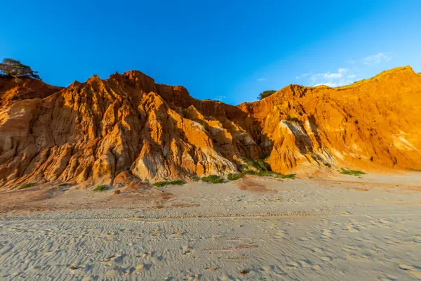 Bir çakıl taşı ve kumsalda inanılmaz kaya oluşumu. Kızıl topraklı kızıl kayalıklar ve kumlu sahilde inanılmaz oluşumlar. Praia da Falsia, sıcak güneş ışığıyla yıkanmış, Algarve, Portekiz