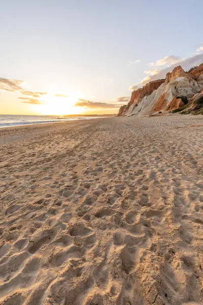 Okyanus kıyısında inanılmaz bir kaya oluşumu. Kızıl toprağı ve geniş kumsalda çarpıcı oluşumları olan kızıl kayalıklar. Praia da Falsia, güneş batarken sıcak bir ışıkta yıkandı, Algarve, Portekiz