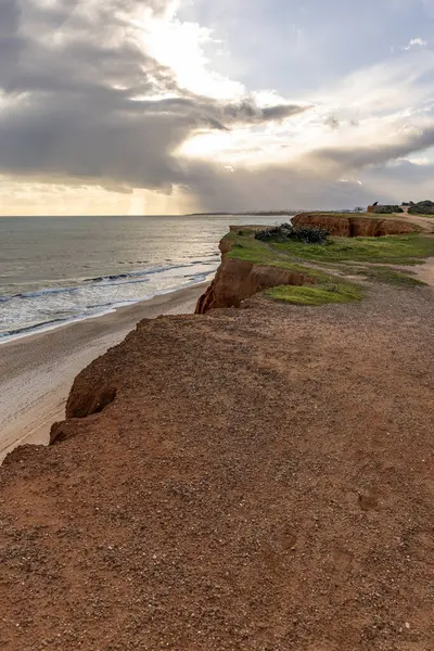 Atlantik Okyanusu 'nda çarpıcı oluşumları olan kayalıklar. Manzara çekiminde sıcak gün batımı. Sahilde ve denizde çarpıcı oluşumlara sahip kızıl kayalıklar, Praia da Falsia, Algarve, Portekiz
