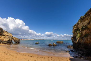 Kumsaldaki sarı kayalar ve uçurumlar. Eski Pinhao Fort Köprüsü 'nün iki uçurumu birleştirdiği deniz kenarında bir koy. Praia da Caldeira plajı, Lagos. Algarve, Portekiz