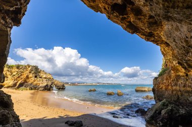 Kumsaldaki sarı kayalar ve uçurumlar. Eski Pinhao Fort Köprüsü 'nün iki uçurumu birleştirdiği deniz kenarında bir koy. Praia da Caldeira plajı, Lagos. Algarve, Portekiz