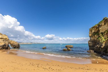 Kumsaldaki sarı kayalar ve uçurumlar. Eski Pinhao Fort Köprüsü 'nün iki uçurumu birleştirdiği deniz kenarında bir koy. Praia da Caldeira plajı, Lagos. Algarve, Portekiz