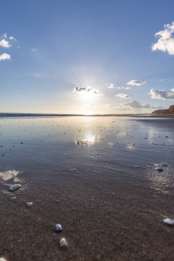 Praia da Falsia 'nın altın kumlu plajı, gökyüzünün yansıması ile kristal berraklığında deniz suyu, batan güneş, ve karakteristik turuncu kayalıklar, Algarve, Portekiz