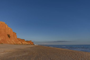 Praia da Falsia 'nın altın kumlu plajı. Karakteristik turuncu uçurumları. Akşam üzeri Portekiz' in Algarve kentindeki uçurumlarda çekilen manzara.