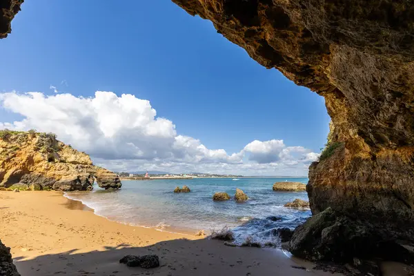 Kumsaldaki sarı kayalar ve uçurumlar. Eski Pinhao Fort Köprüsü 'nün iki uçurumu birleştirdiği deniz kenarında bir koy. Praia da Caldeira plajı, Lagos. Algarve, Portekiz