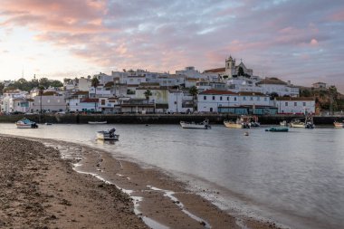 Kumsala bakan bir gün doğumu ve alçak gelgitte liman. Günbatımında Ferragudo, Portimo, Algarve, Portekiz 'de tarihi bir kasabanın panoramik manzarası