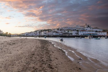 Kumsala bakan bir gün doğumu ve alçak gelgitte liman. Günbatımında Ferragudo, Portimo, Algarve, Portekiz 'de tarihi bir kasabanın panoramik manzarası