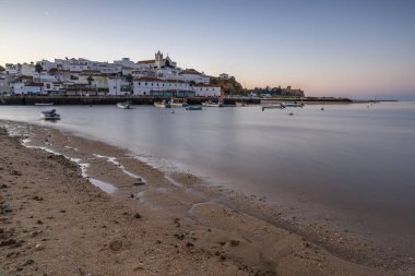 Kumsala bakan bir gün doğumu ve alçak gelgitte liman. Günbatımında Ferragudo, Portimo, Algarve, Portekiz 'de tarihi bir kasabanın panoramik manzarası
