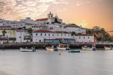 Kumsala bakan bir gün doğumu ve alçak gelgitte liman. Günbatımında Ferragudo, Portimo, Algarve, Portekiz 'de tarihi bir kasabanın panoramik manzarası