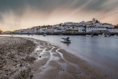 Kumsala bakan bir gün doğumu ve alçak gelgitte liman. Günbatımında Ferragudo, Portimo, Algarve, Portekiz 'de tarihi bir kasabanın panoramik manzarası