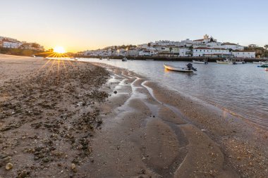 Kumsala bakan bir gün doğumu ve alçak gelgitte liman. Ferragudo, Portimo, Algarve, Portekiz 'deki tarihi bir kasabanın panoramik sabah manzarası