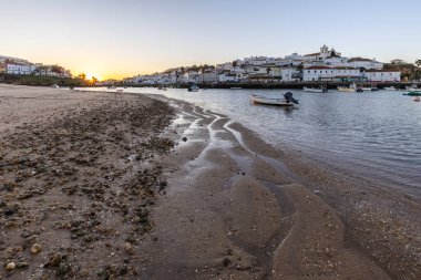 Kumsala bakan bir gün doğumu ve alçak gelgitte liman. Ferragudo, Portimo, Algarve, Portekiz 'deki tarihi bir kasabanın panoramik sabah manzarası