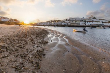 Kumsala bakan bir gün doğumu ve alçak gelgitte liman. Ferragudo, Portimo, Algarve, Portekiz 'deki tarihi bir kasabanın panoramik sabah manzarası