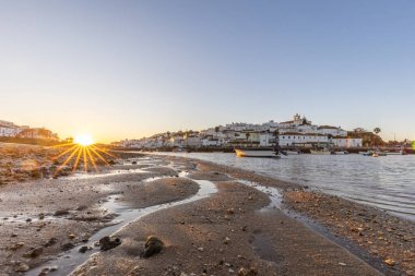 Kumsala bakan bir gün doğumu ve alçak gelgitte liman. Ferragudo, Portimo, Algarve, Portekiz 'deki tarihi bir kasabanın panoramik sabah manzarası