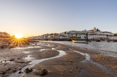 Kumsala bakan bir gün doğumu ve alçak gelgitte liman. Ferragudo, Portimo, Algarve, Portekiz 'deki tarihi bir kasabanın panoramik sabah manzarası