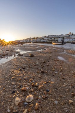 Kumsala bakan bir gün doğumu ve alçak gelgitte liman. Ferragudo, Portimo, Algarve, Portekiz 'deki tarihi bir kasabanın panoramik sabah manzarası