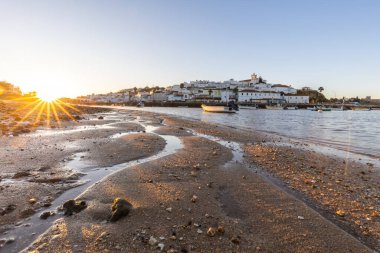 Kumsala bakan bir gün doğumu ve alçak gelgitte liman. Ferragudo, Portimo, Algarve, Portekiz 'deki tarihi bir kasabanın panoramik sabah manzarası