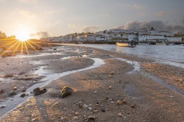 Kumsala bakan bir gün doğumu ve alçak gelgitte liman. Ferragudo, Portimo, Algarve, Portekiz 'deki tarihi bir kasabanın panoramik sabah manzarası