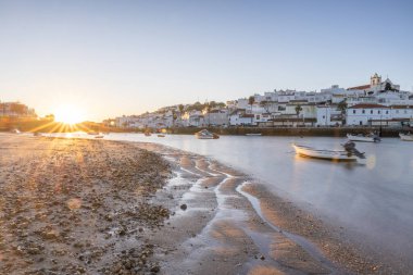 Kumsala bakan bir gün doğumu ve alçak gelgitte liman. Ferragudo, Portimo, Algarve, Portekiz 'deki tarihi bir kasabanın panoramik sabah manzarası