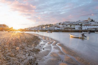 Kumsala bakan bir gün doğumu ve alçak gelgitte liman. Ferragudo, Portimo, Algarve, Portekiz 'deki tarihi bir kasabanın panoramik sabah manzarası