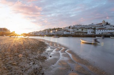 Kumsala bakan bir gün doğumu ve alçak gelgitte liman. Ferragudo, Portimo, Algarve, Portekiz 'deki tarihi bir kasabanın panoramik sabah manzarası
