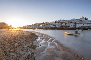 Kumsala bakan bir gün doğumu ve alçak gelgitte liman. Ferragudo, Portimo, Algarve, Portekiz 'deki tarihi bir kasabanın panoramik sabah manzarası