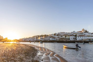Kumsala bakan bir gün doğumu ve alçak gelgitte liman. Ferragudo, Portimo, Algarve, Portekiz 'deki tarihi bir kasabanın panoramik sabah manzarası