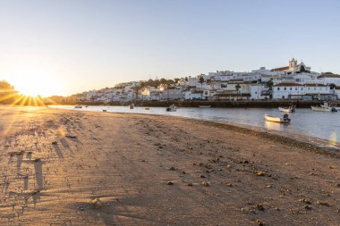 Kumsala bakan bir gün doğumu ve alçak gelgitte liman. Ferragudo, Portimo, Algarve, Portekiz 'deki tarihi bir kasabanın panoramik sabah manzarası