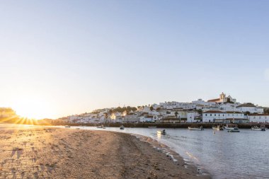 Kumsala bakan bir gün doğumu ve alçak gelgitte liman. Ferragudo, Portimo, Algarve, Portekiz 'deki tarihi bir kasabanın panoramik sabah manzarası