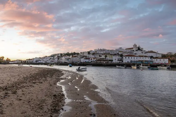 Kumsala bakan bir gün doğumu ve alçak gelgitte liman. Günbatımında Ferragudo, Portimo, Algarve, Portekiz 'de tarihi bir kasabanın panoramik manzarası
