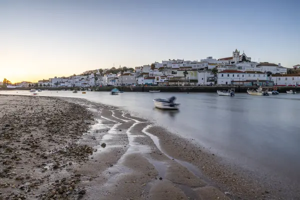 Kumsala bakan bir gün doğumu ve alçak gelgitte liman. Günbatımında Ferragudo, Portimo, Algarve, Portekiz 'de tarihi bir kasabanın panoramik manzarası