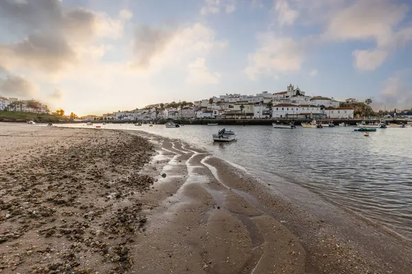 Kumsala bakan bir gün doğumu ve alçak gelgitte liman. Günbatımında Ferragudo, Portimo, Algarve, Portekiz 'de tarihi bir kasabanın panoramik manzarası