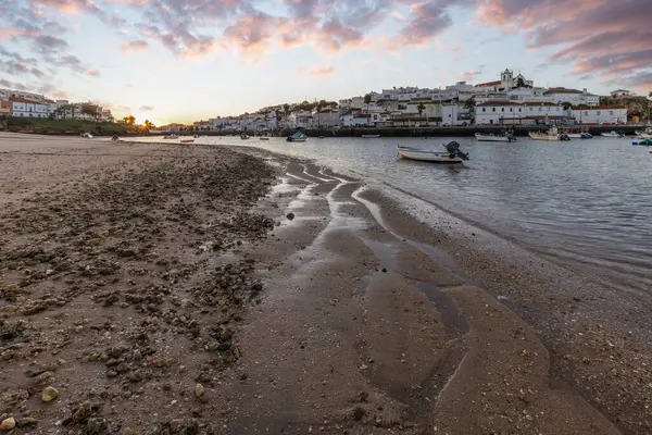 Kumsala bakan bir gün doğumu ve alçak gelgitte liman. Günbatımında Ferragudo, Portimo, Algarve, Portekiz 'de tarihi bir kasabanın panoramik manzarası