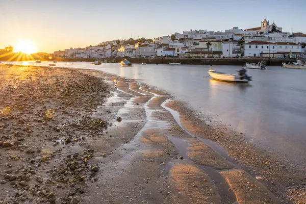Kumsala bakan bir gün doğumu ve alçak gelgitte liman. Ferragudo, Portimo, Algarve, Portekiz 'deki tarihi bir kasabanın panoramik sabah manzarası