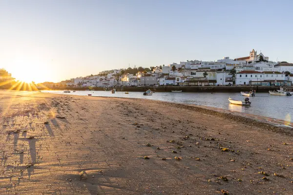 Kumsala bakan bir gün doğumu ve alçak gelgitte liman. Ferragudo, Portimo, Algarve, Portekiz 'deki tarihi bir kasabanın panoramik sabah manzarası