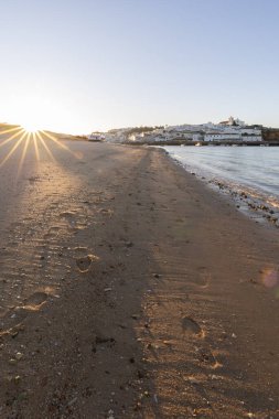 Atlantik Okyanusu 'nda gün doğumu, limanın arkasındaki balıkçı köyünün silueti. Sabah alacakaranlıkta kumsalda. Ferragudo, Portimo, Algarve, Portekiz 'de manzara çekimi