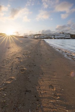 Atlantik Okyanusu 'nda gün doğumu, limanın arkasındaki balıkçı köyünün silueti. Sabah alacakaranlıkta kumsalda. Ferragudo, Portimo, Algarve, Portekiz 'de manzara çekimi