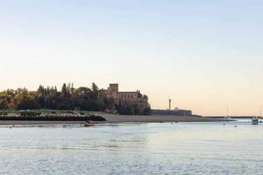 Atlantik 'te gün doğumu, sahilin ortasında bir kale. Limanı koruyan tarihi bir bina. Castelo de Ferragudo, kumlu Praia da Angrinha sahilinde, Portimo, Algarve, Portekiz