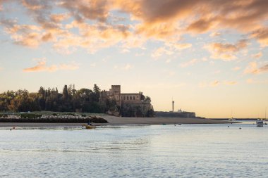 Atlantik 'te gün doğumu, sahilin ortasında bir kale. Limanı koruyan tarihi bir bina. Castelo de Ferragudo, kumlu Praia da Angrinha sahilinde, Portimo, Algarve, Portekiz