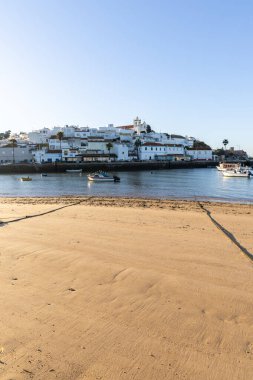 Atlantik Okyanusu 'nda gün doğumu, limanın arkasındaki balıkçı köyünün silueti. Sabah alacakaranlıkta kumsalda. Ferragudo, Portimo, Algarve, Portekiz 'de manzara çekimi