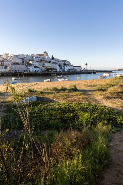 Güneşin doğuşu çayıra, kumlu plaja ve alçak gelgitte limana bakıyor. Günbatımında Ferragudo, Portimo, Algarve, Portekiz 'de tarihi bir kasabanın panoramik manzarası