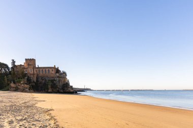 Atlantik 'te gün doğumu, sahilin ortasında bir kale. Limanı koruyan tarihi bir bina. Castelo de Ferragudo, kumlu Praia da Angrinha sahilinde, Portimo, Algarve, Portekiz