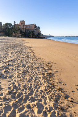 Atlantik 'te gün doğumu, sahilin ortasında bir kale. Limanı koruyan tarihi bir bina. Castelo de Ferragudo, kumlu Praia da Angrinha sahilinde, Portimo, Algarve, Portekiz