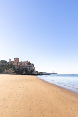 Atlantik 'te gün doğumu, sahilin ortasında bir kale. Limanı koruyan tarihi bir bina. Castelo de Ferragudo, kumlu Praia da Angrinha sahilinde, Portimo, Algarve, Portekiz